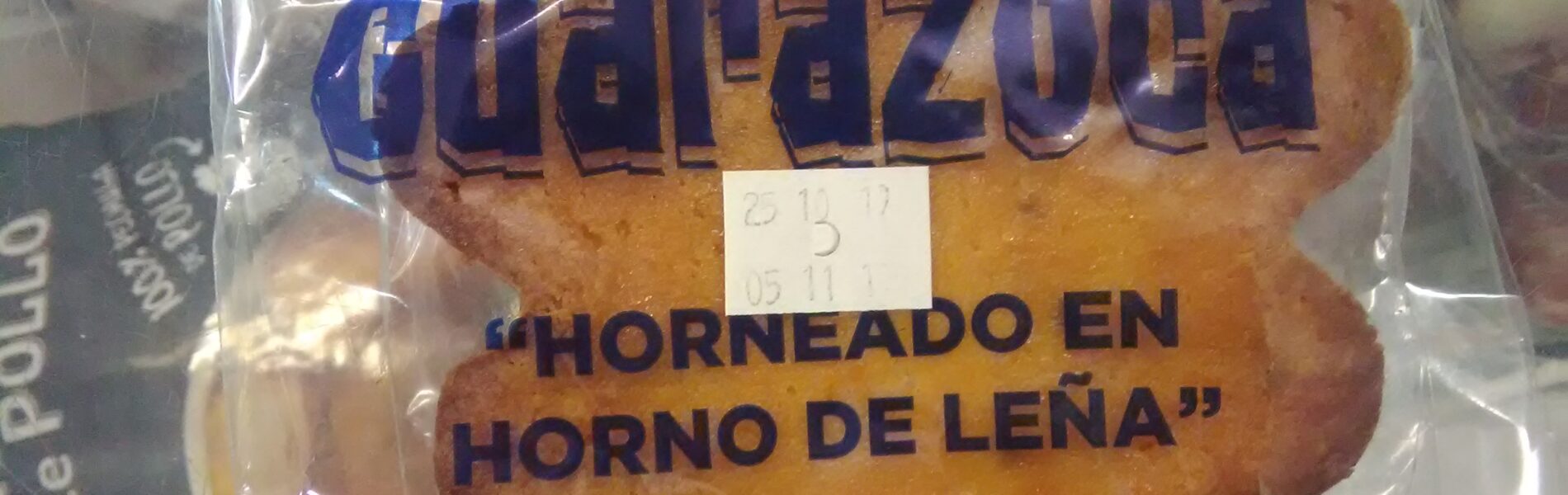 Packaged quesadilla with blue label text reading 'Quesadilla Guarazoca' and 'Horneado en Horno de Leña', baked goods visible inside plastic wrapper.