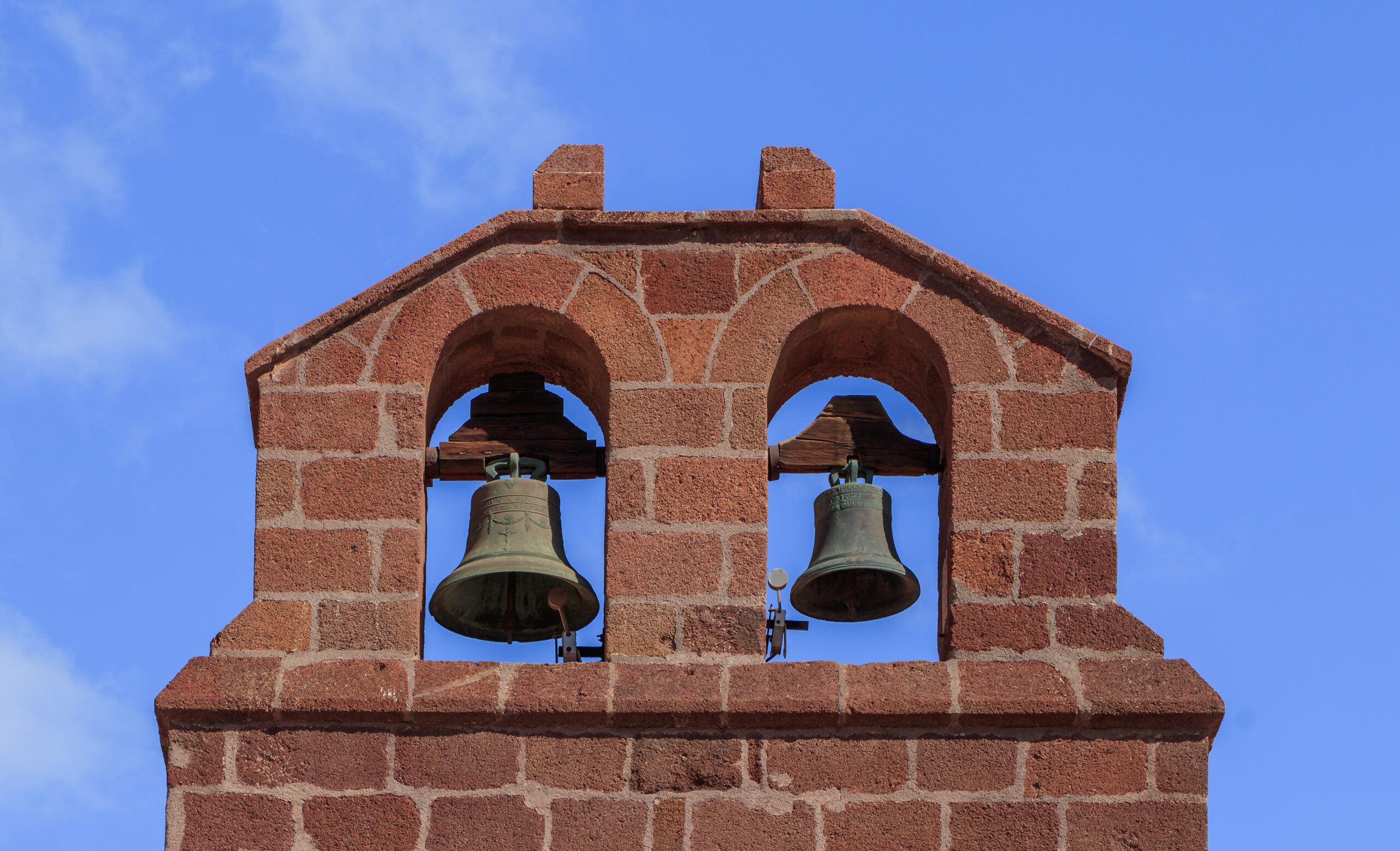 The distinctive red brick bell tower of San Sebastián’s Old Town, featuring two bronze bells mounted in arched openings.