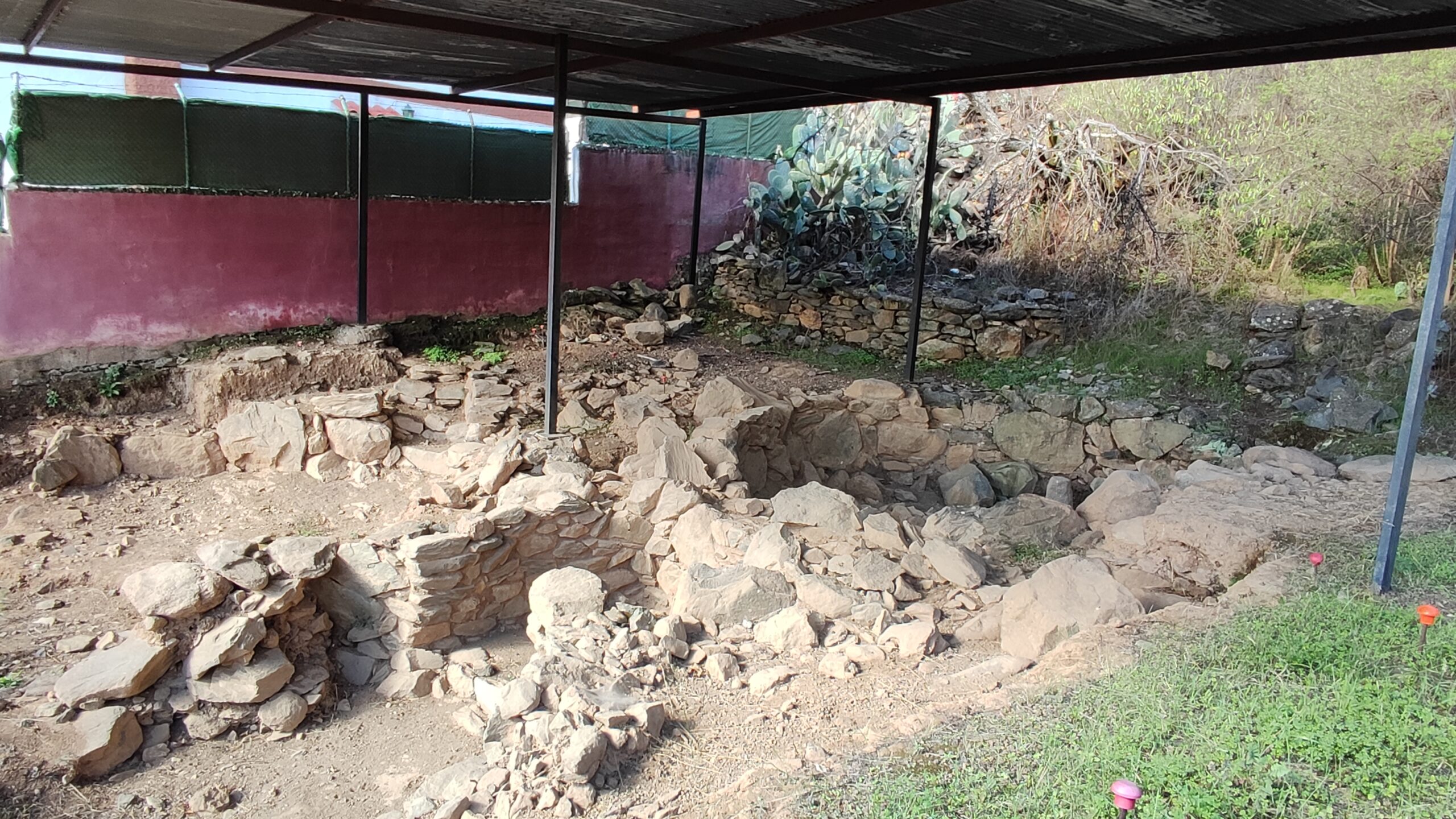 Protected archaeological site displaying ancient stone structures and foundations, sheltered to preserve the remains from weathering.