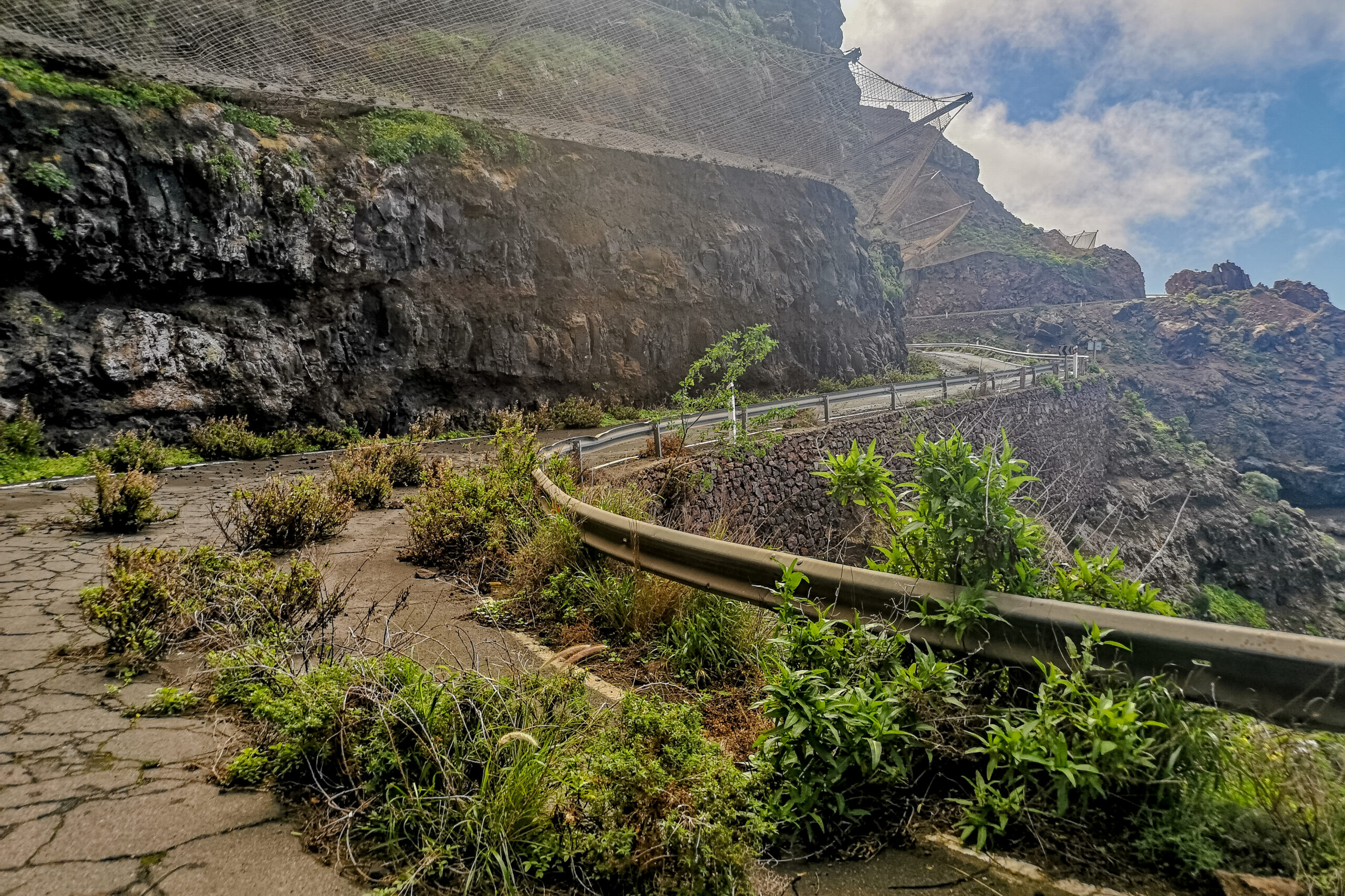 A dramatic volcanic escarpment at Tamadaba Natural Park, with safety railings marking the walking route along the steep cliffside.