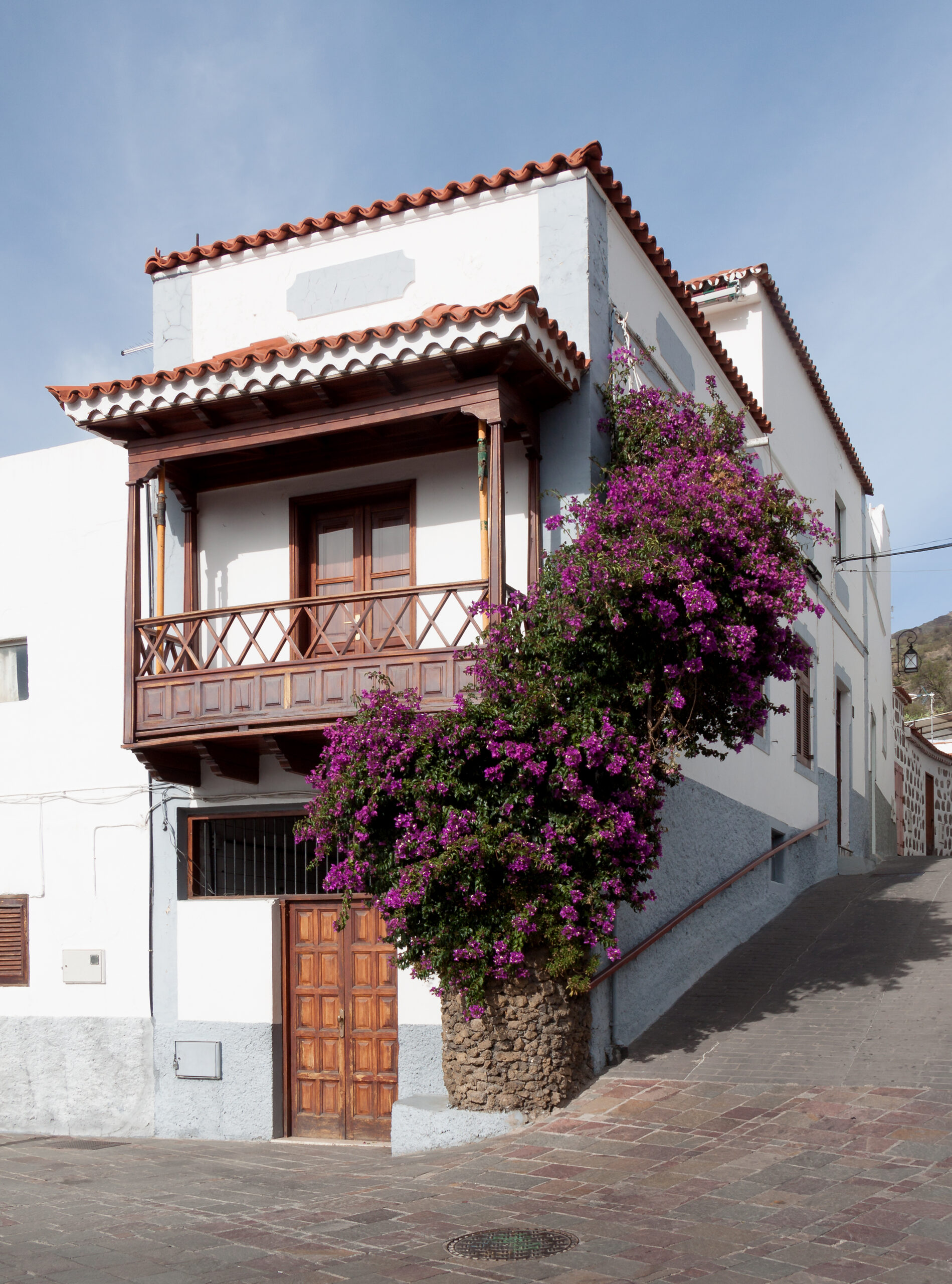 A traditional Canarian house in Tejeda village features whitewashed walls, carved wooden balconies, and vibrant flowering bougainvillea.