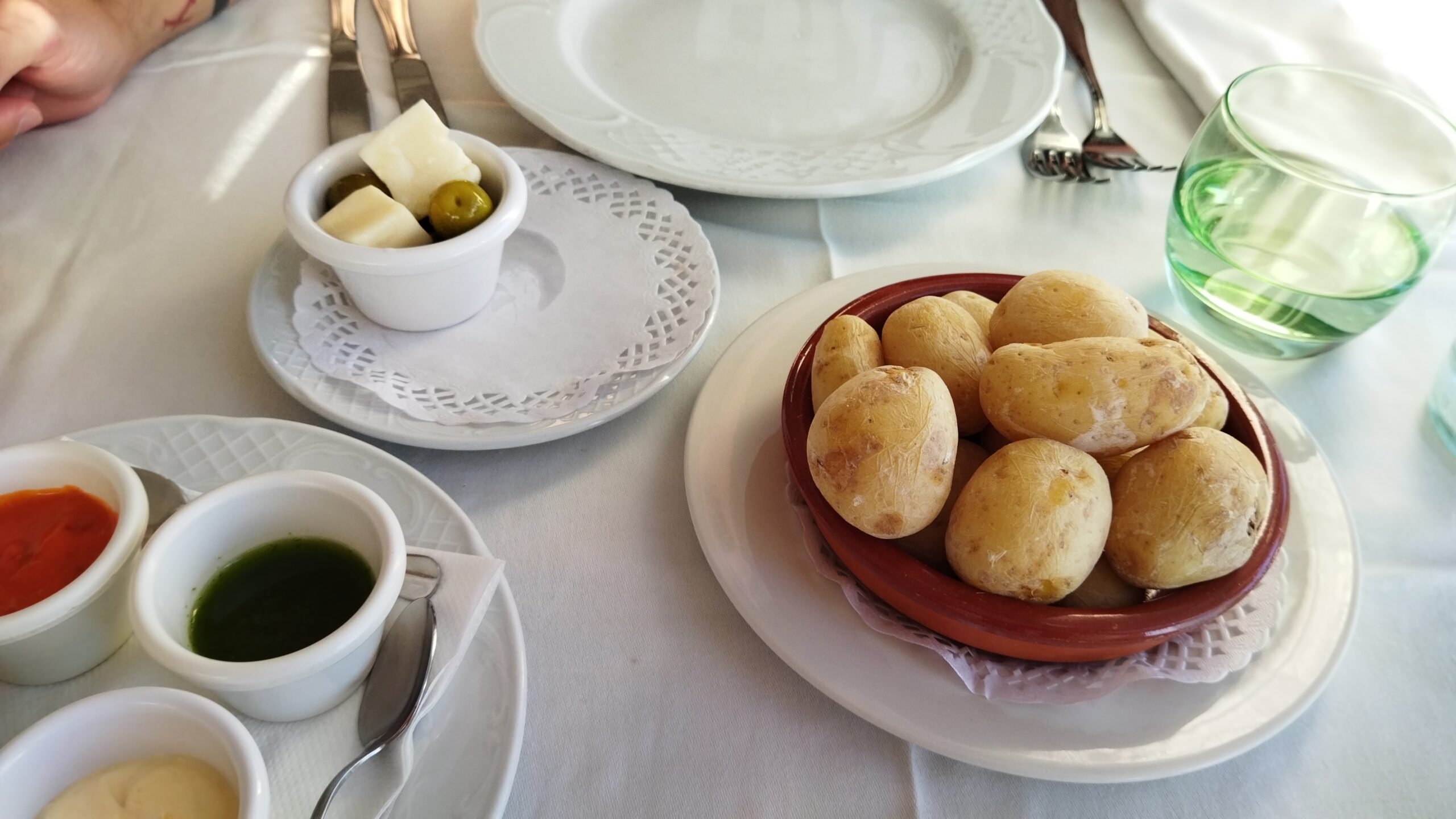 A traditional Canarian restaurant table displays freshly fried bread rolls, house sauces, and appetizers typical of local dining.