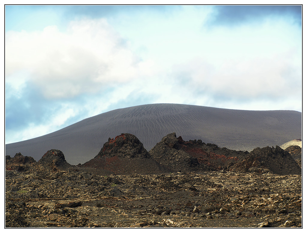 Timanfaya National Park's dramatic volcanic landscape features cinder cones and ancient lava fields that reveal the island's fiery geological history.