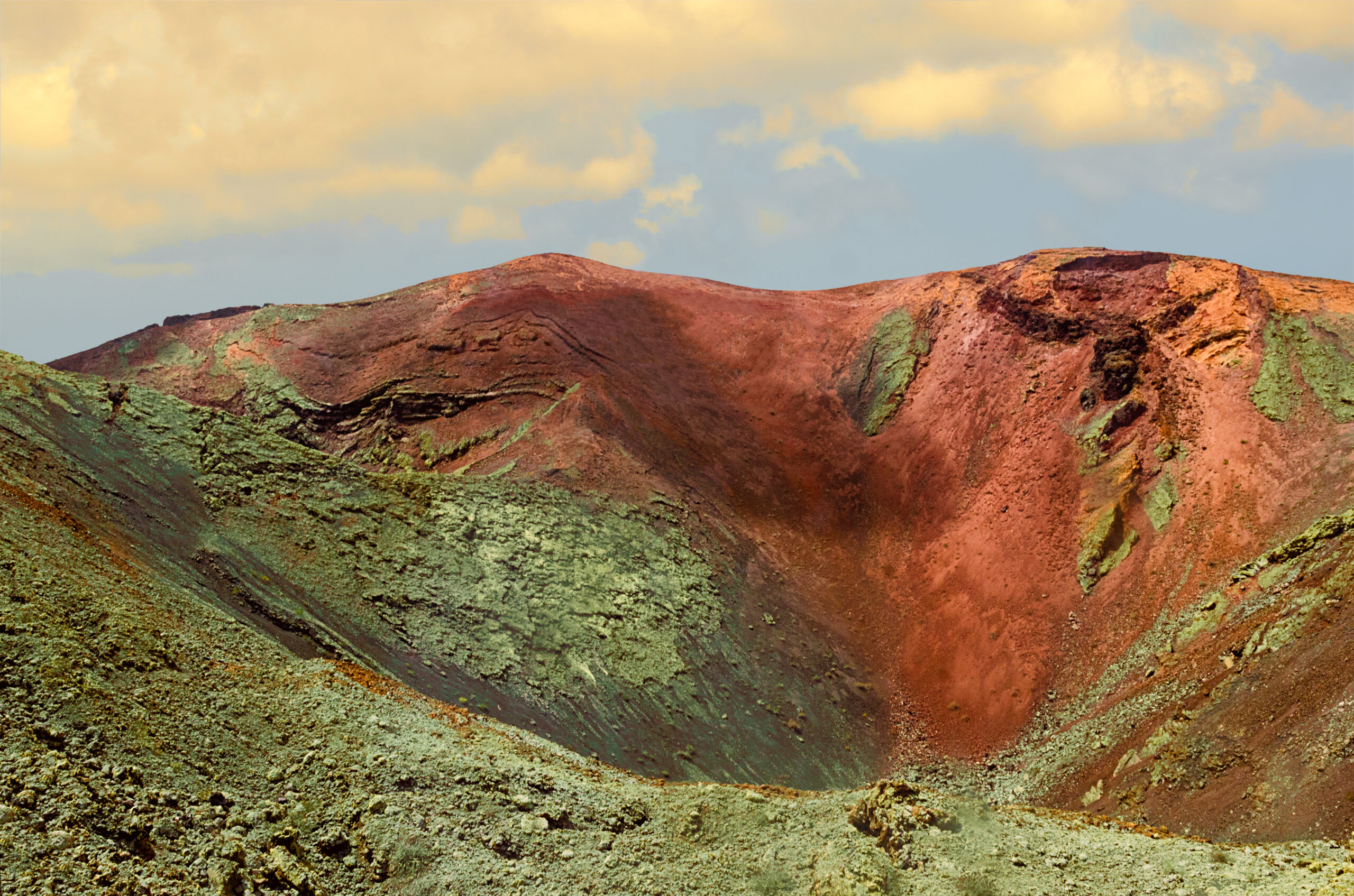 The striking volcanic landscape of Timanfaya National Park reveals dramatic craters with richly colored mineral-stained slopes and sparse vegetation.
