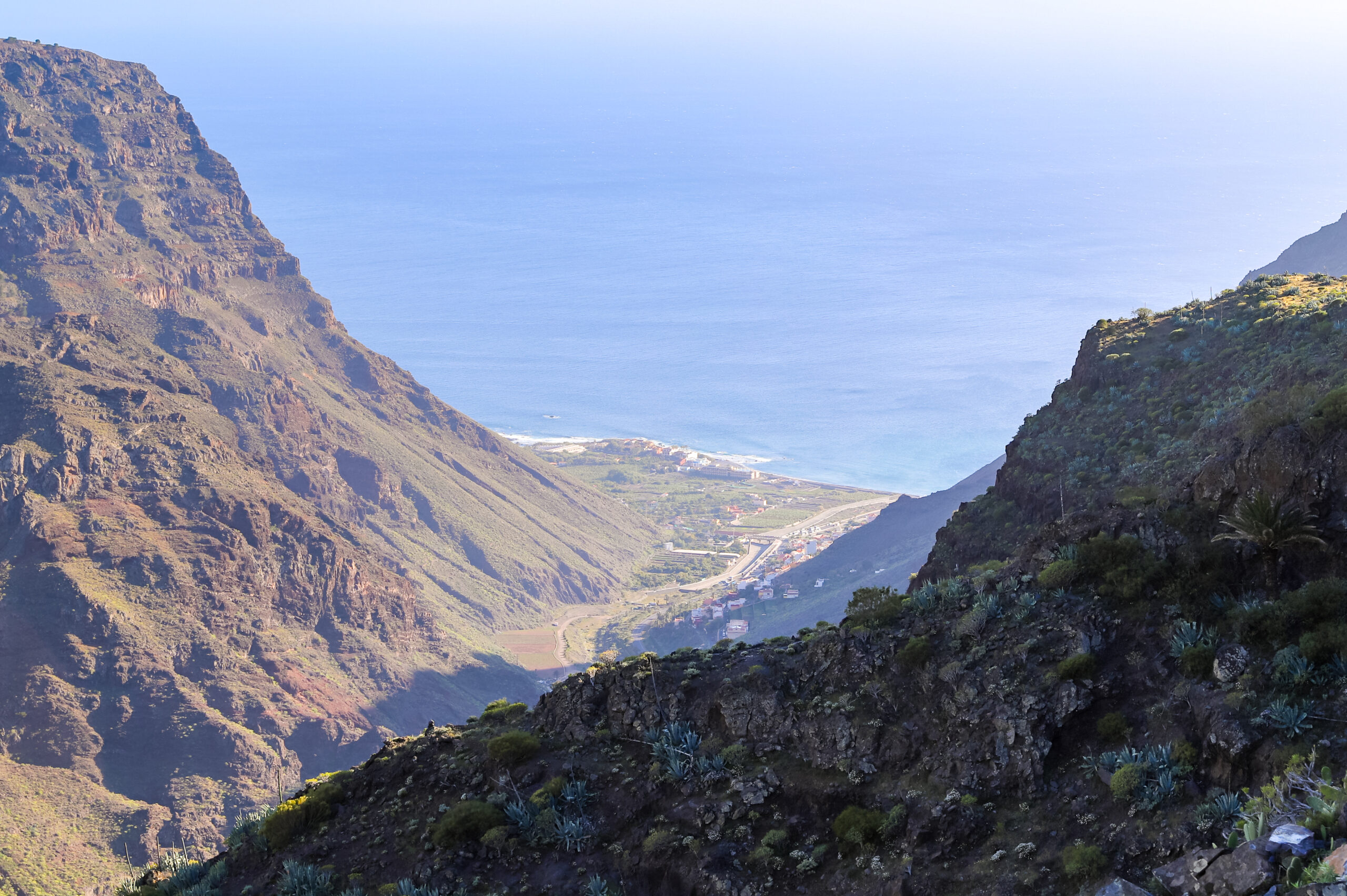 The dramatic landscape of Valle Gran Rey reveals its volcanic origins, with towering cliff faces framing the lush valley settlements below.